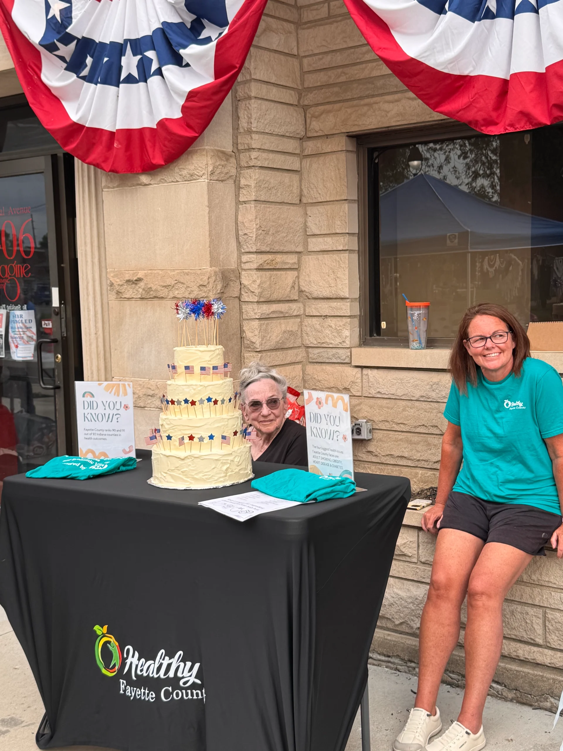 HFC advisor Linda Fitzgerald and board member Nycole Dare welcome attendees with a patriotic USA birthday cake decorates the table.