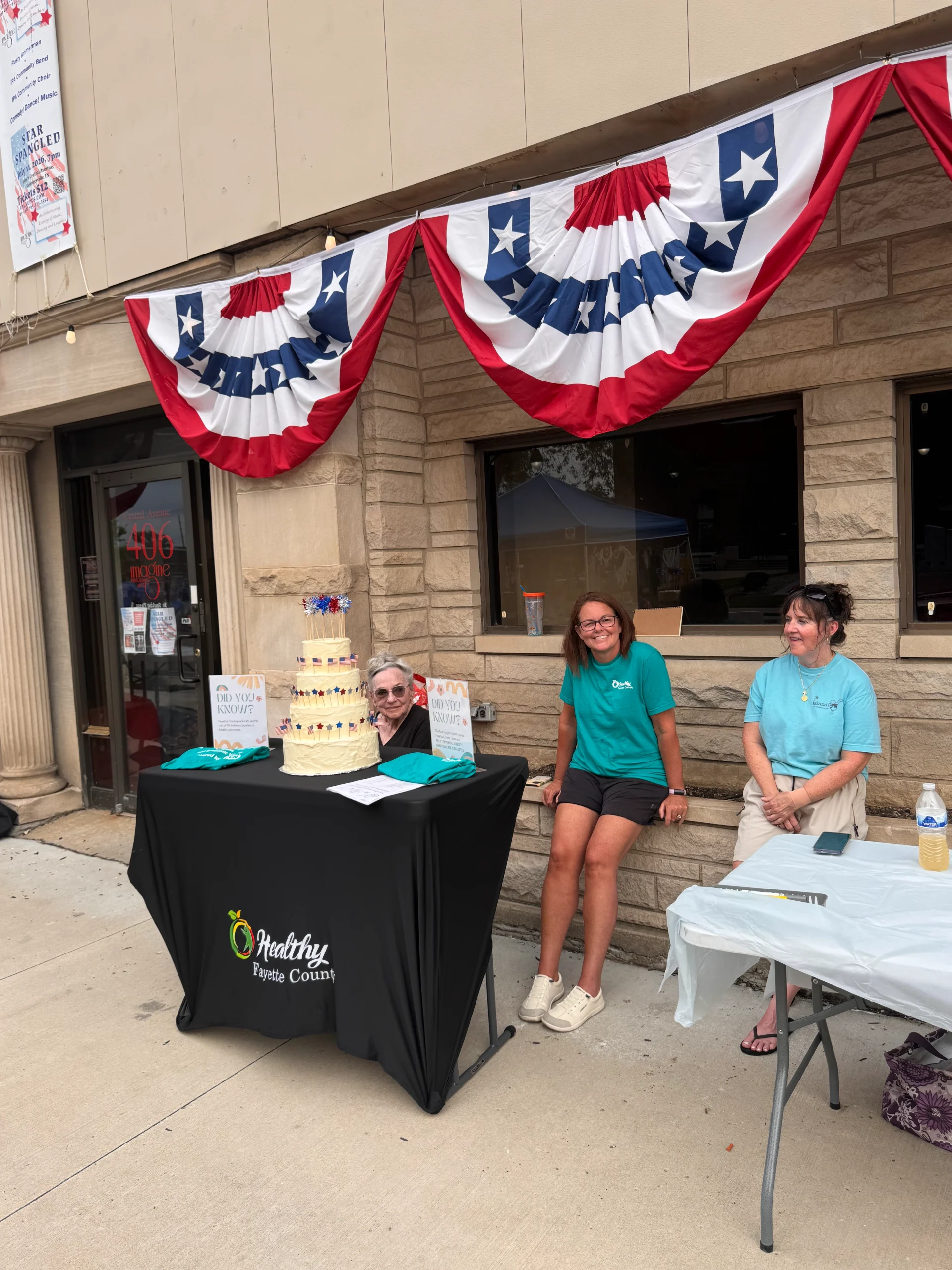 HFC advisor Linda Fitzgerald and board member Nycole Dare welcome attendees with a patriotic USA birthday cake decorates the table.